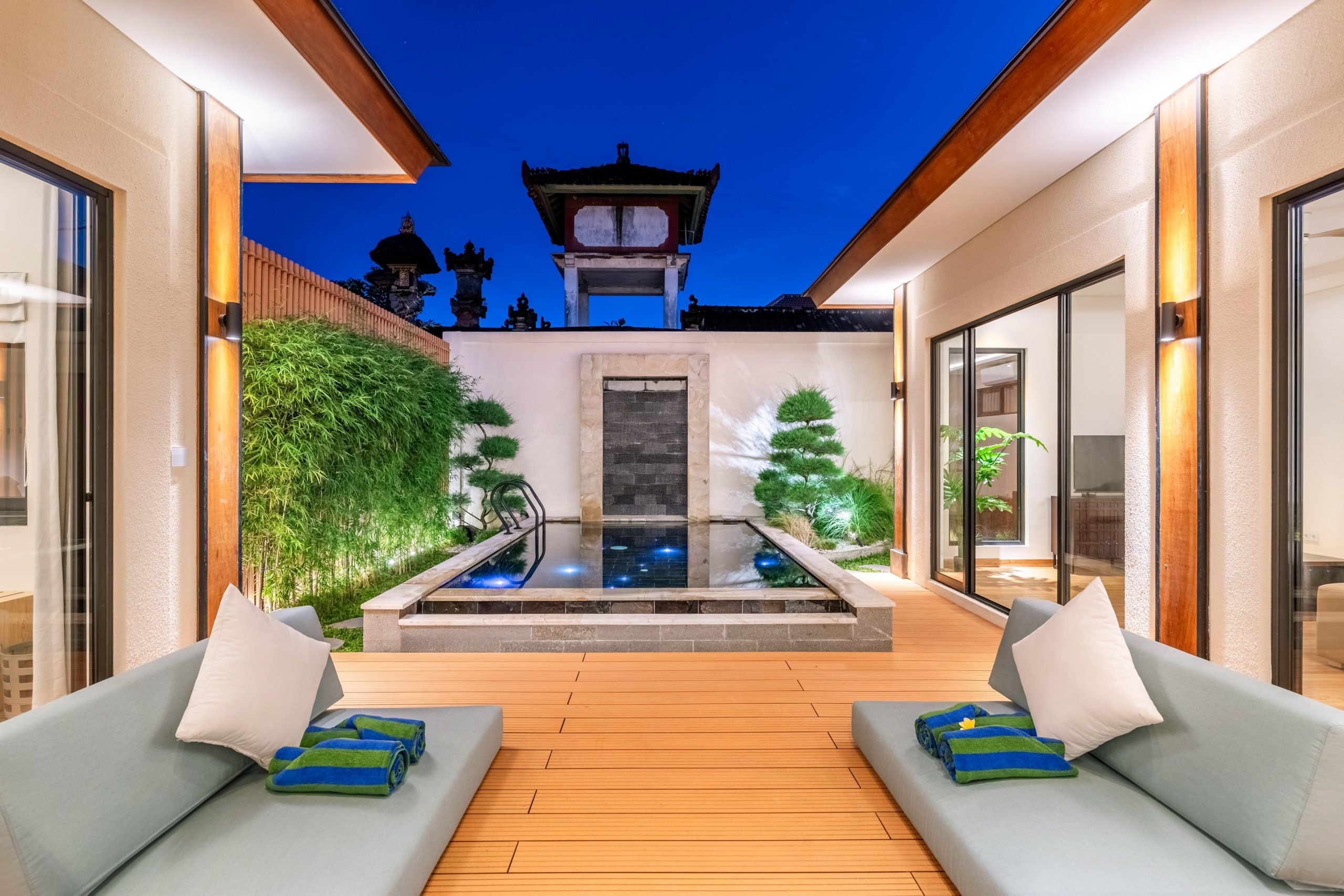 Two daybeds on the deck facing the pool and the temple tower at blue hour