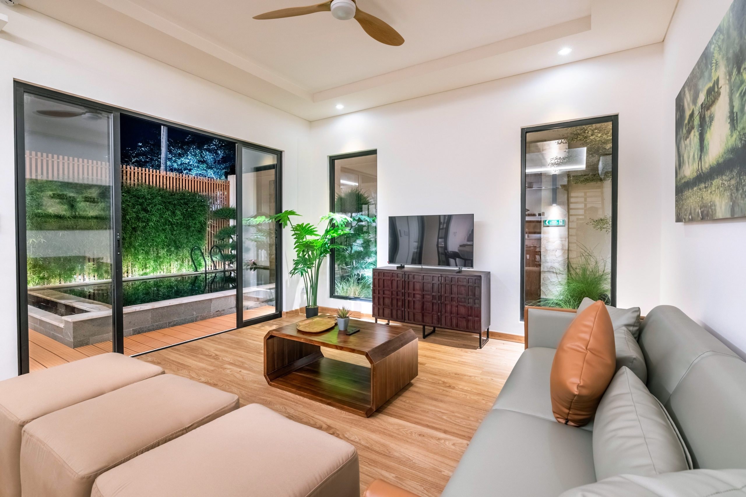 The ground-floor lounge: sofas, TV and the pool garden beyond the glass