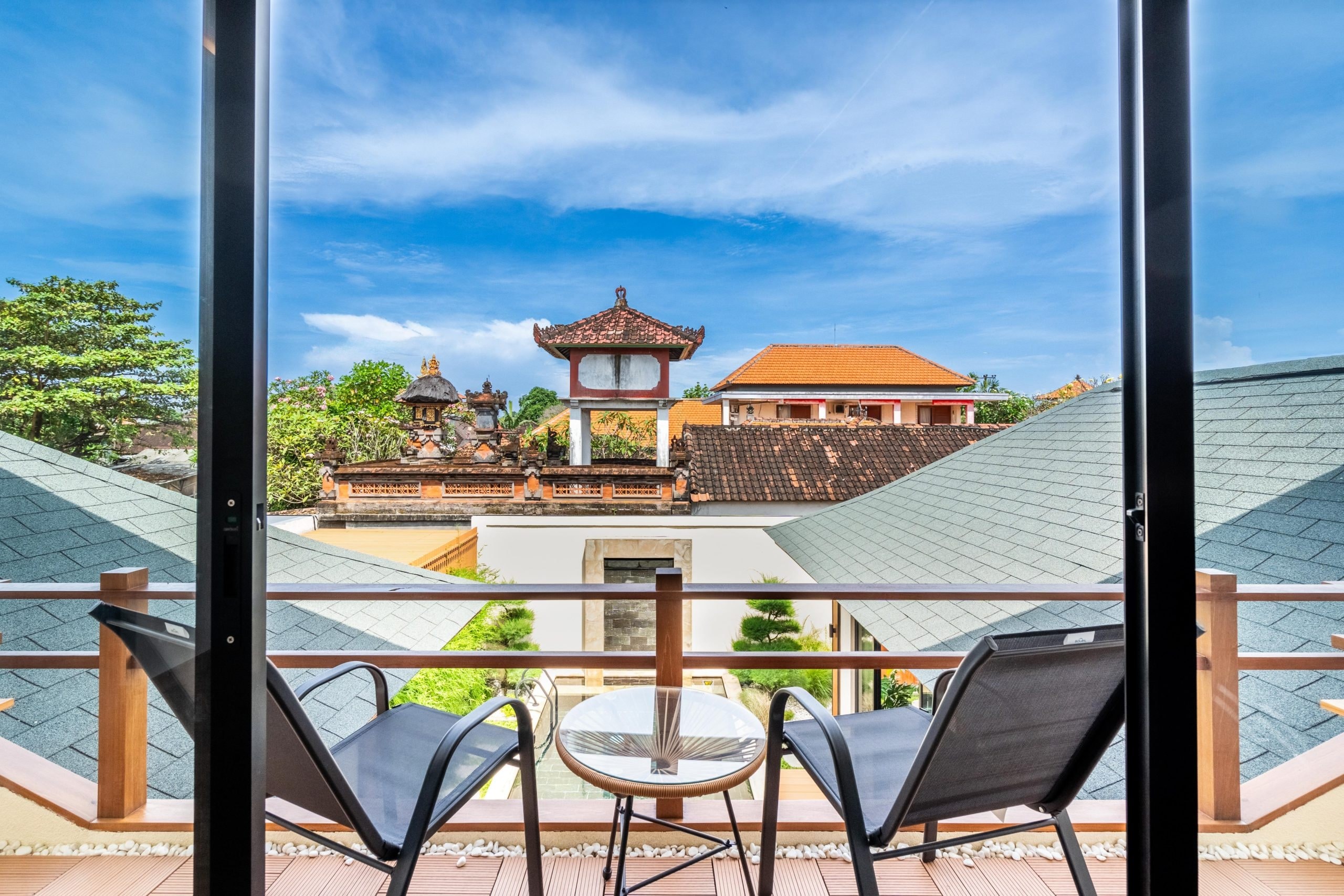 The master balcony through the open doors: two chairs, a small table and the temple tower beyond