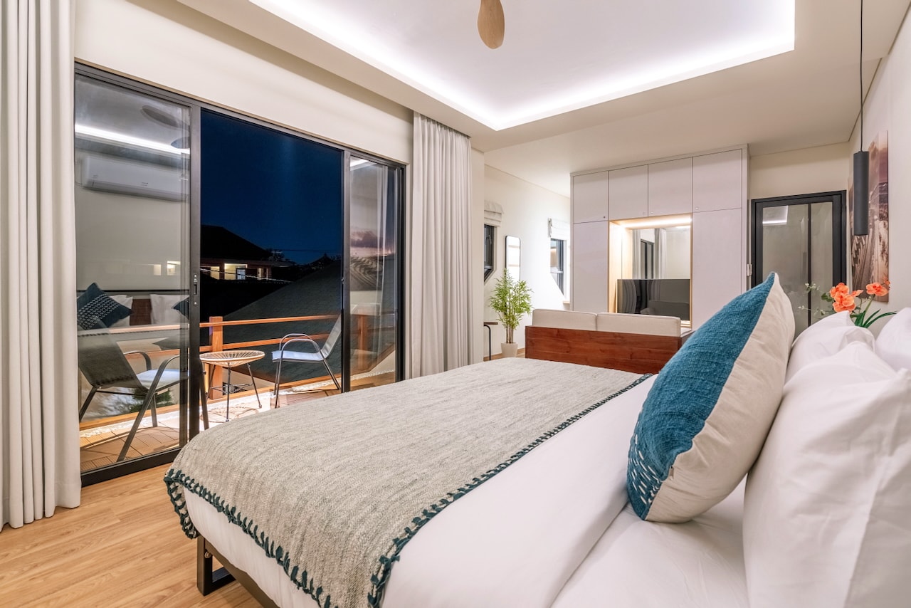 The master bedroom in the evening, the balcony dark blue beyond the glass