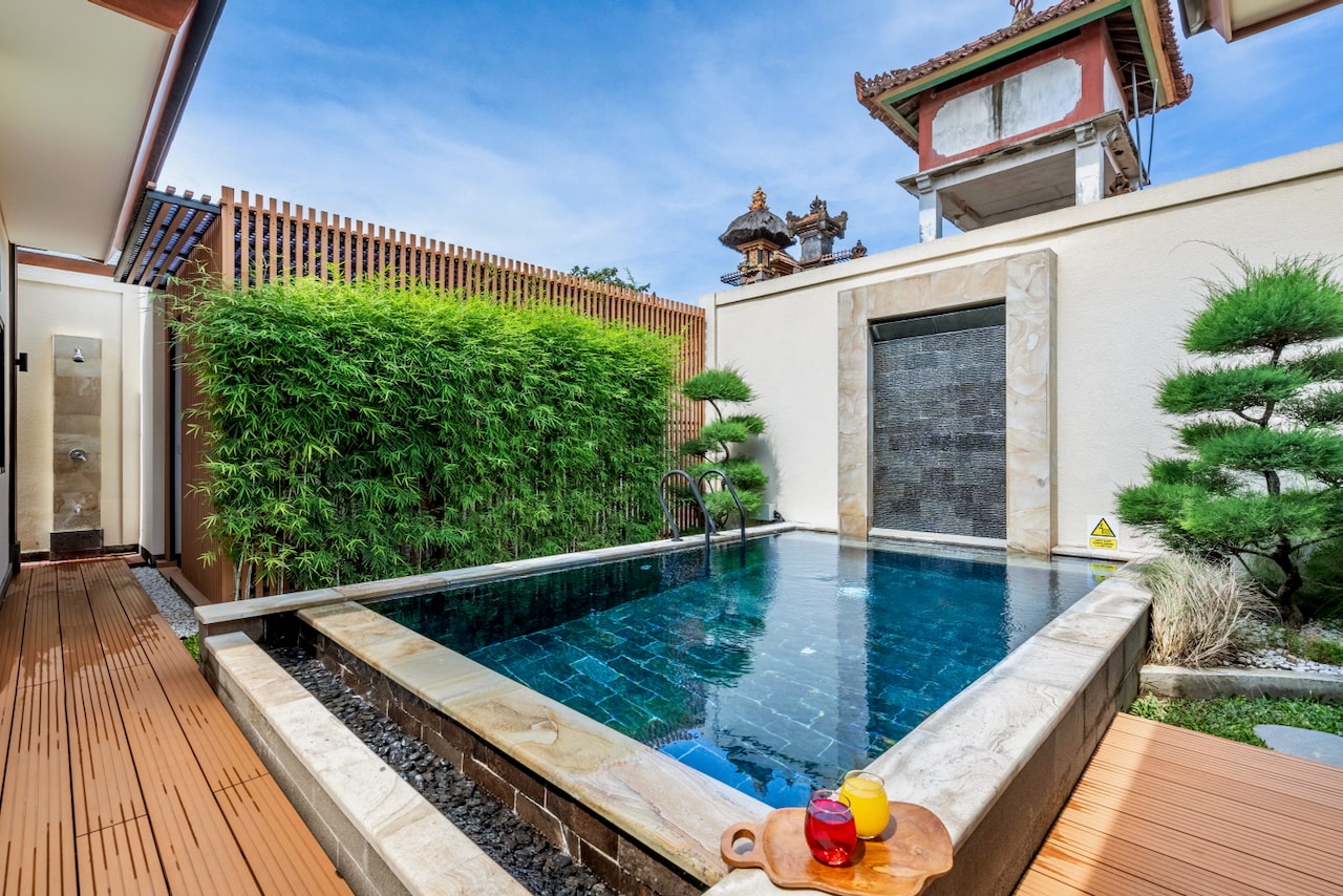 The private green-stone pool and bamboo-walled garden of the villa in Sanur, in morning light