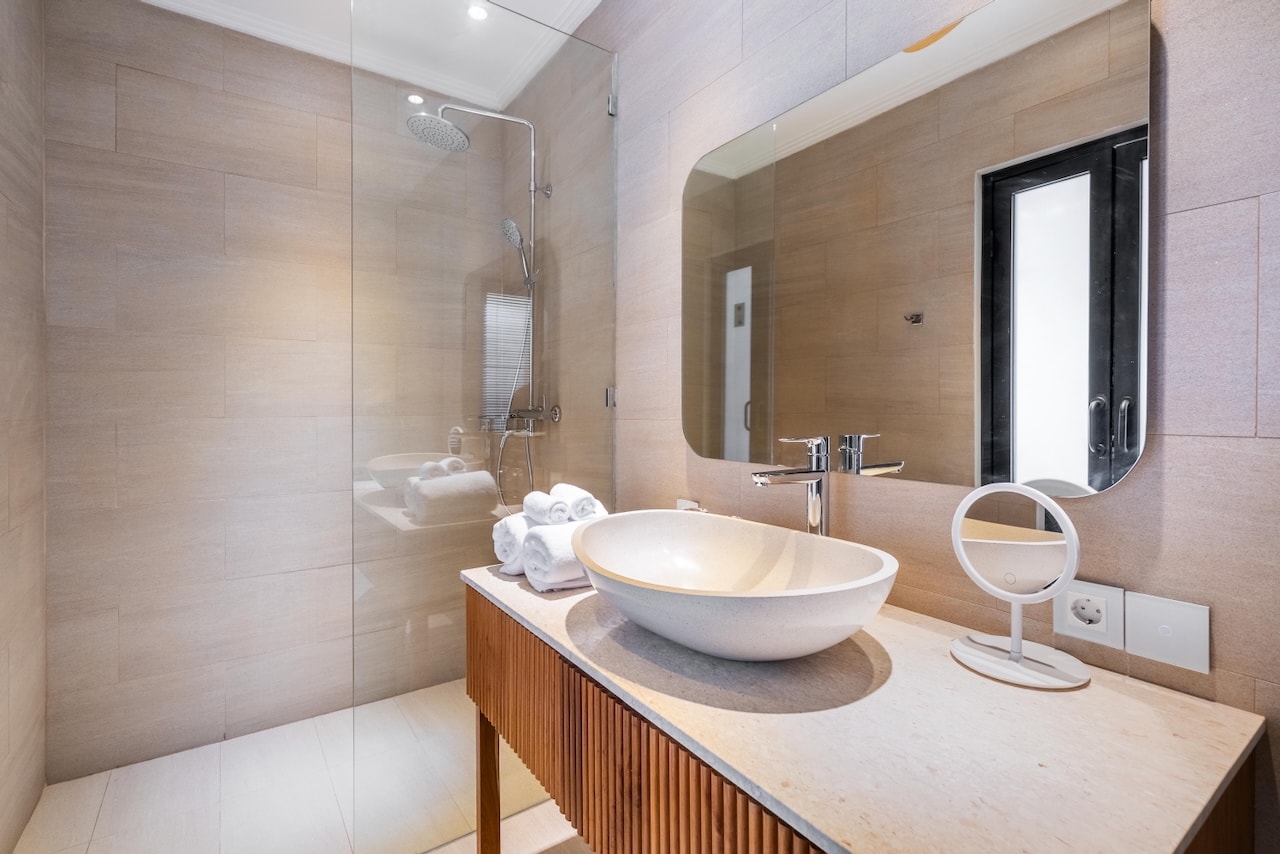 The stone-and-teak en-suite bathroom with rain shower