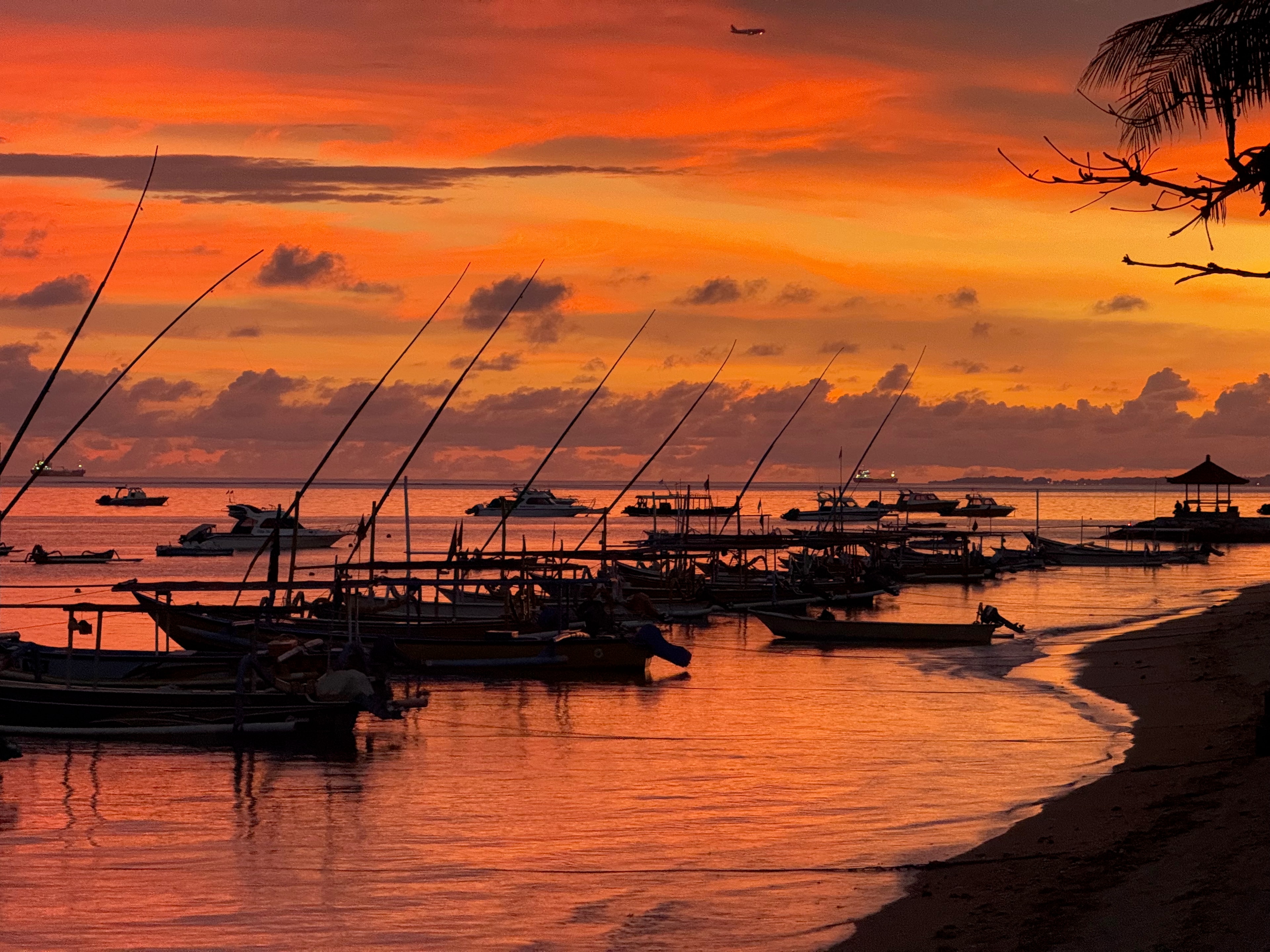 Jukung boats under an orange sky on Sanur beach